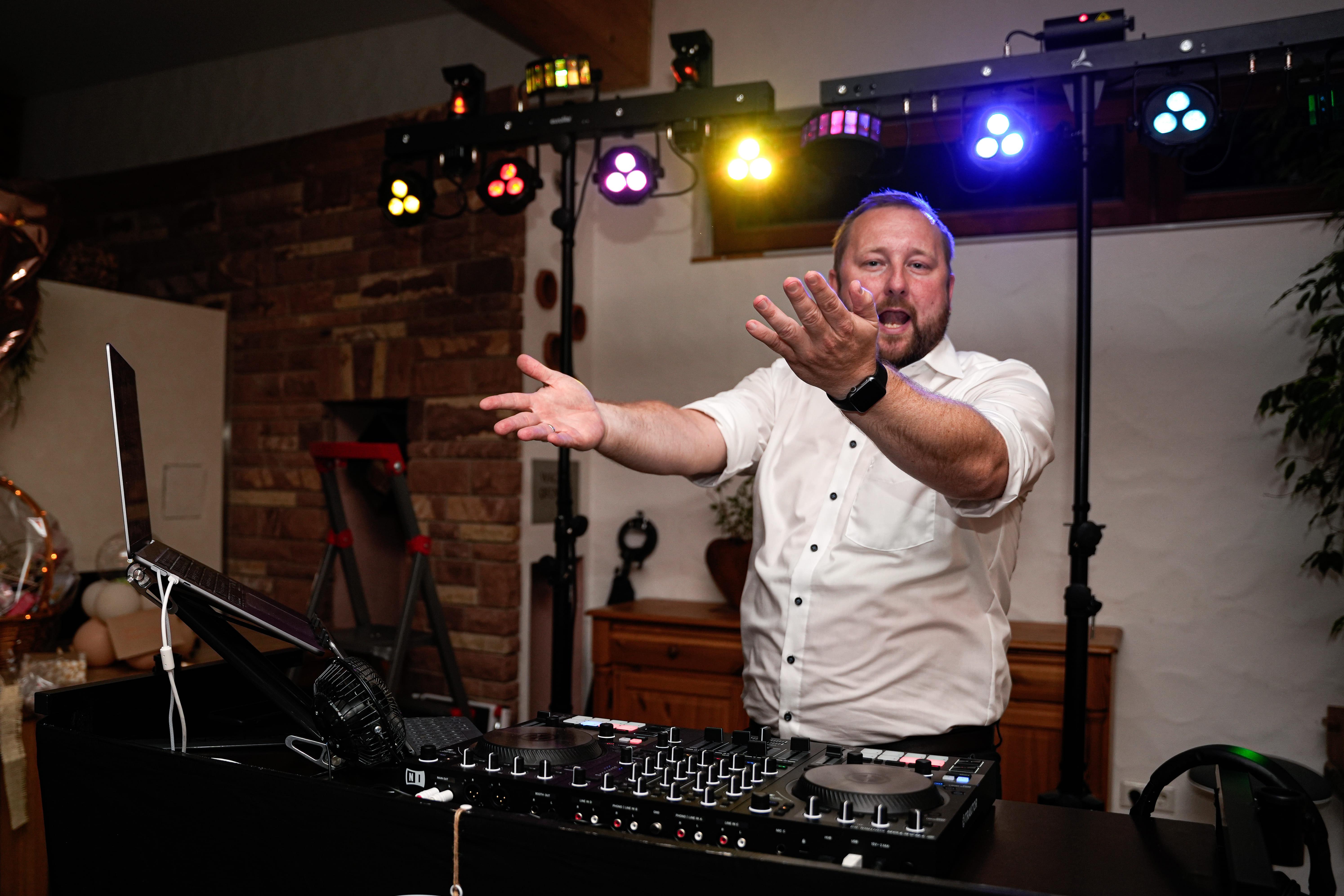 Hochzeits-DJ Tony Lötzke mit weit ausgebreiteten Armen voller Energie am DJ-Pult