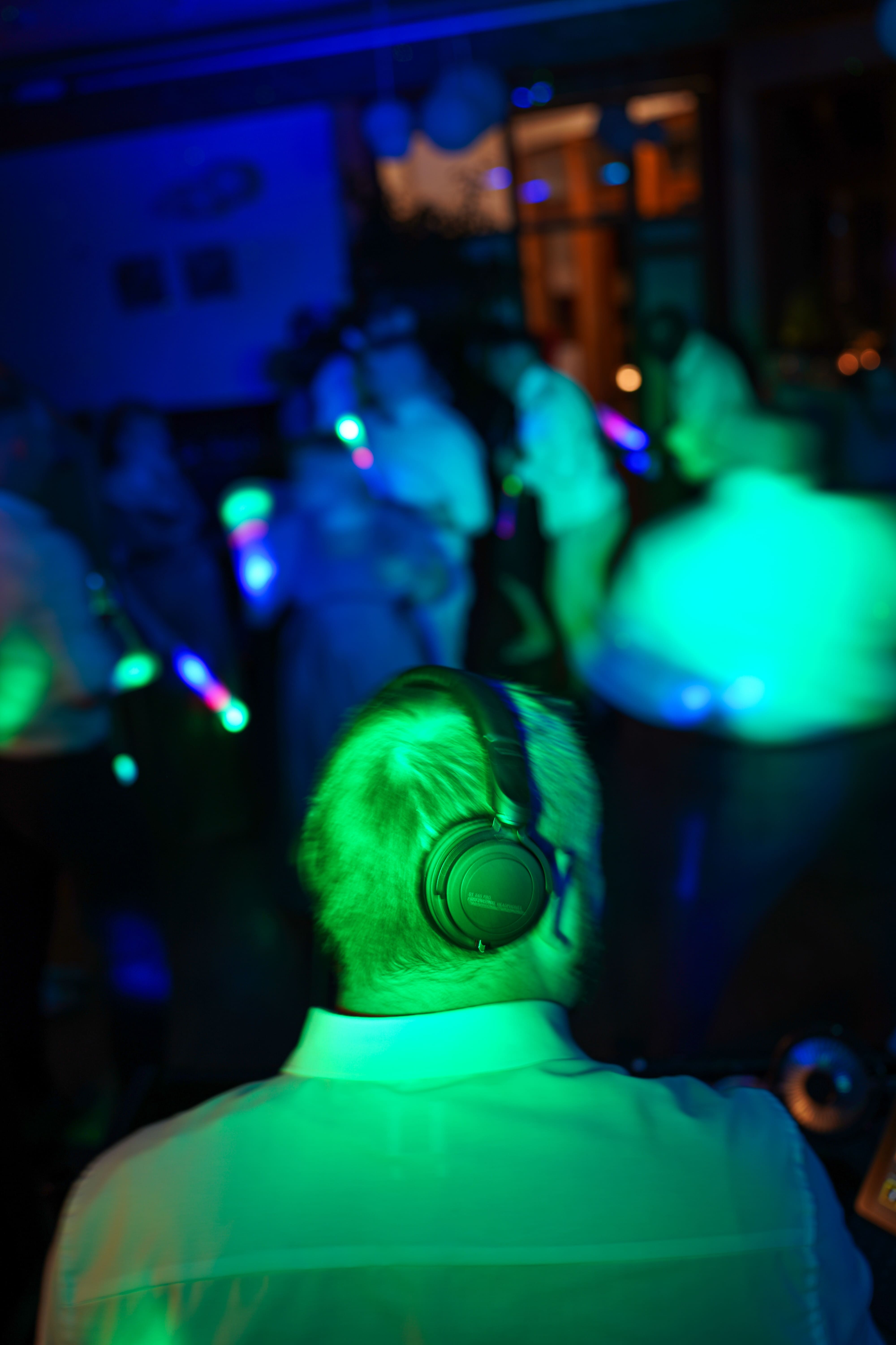 DJ Tony Lötzke von hinten mit Kopfhörern unter grünem Tanzflächenlicht